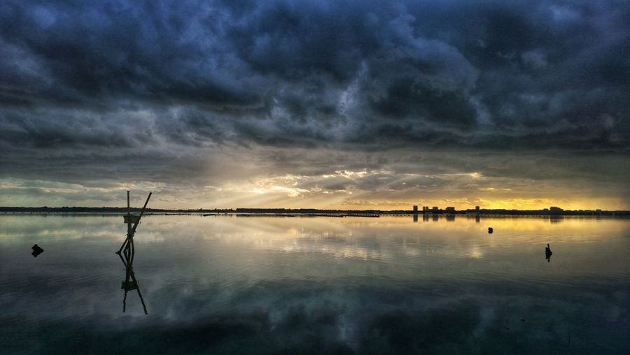 Storm clouds reflecting in sea during sunset