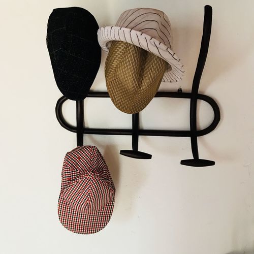 Close-up of hat hanging on table against wall