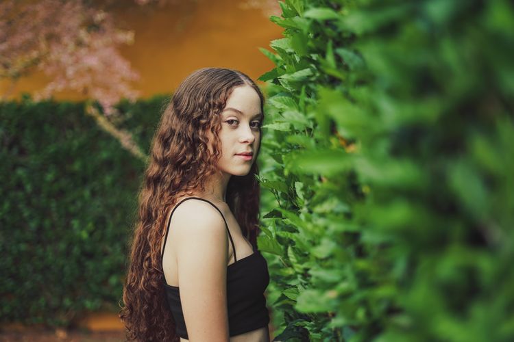 Portrait of teenage girl standing against plants
