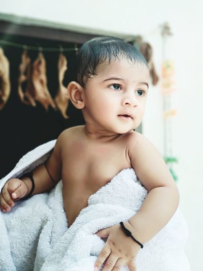 Close-up of shirtless baby boy wrapped in towel