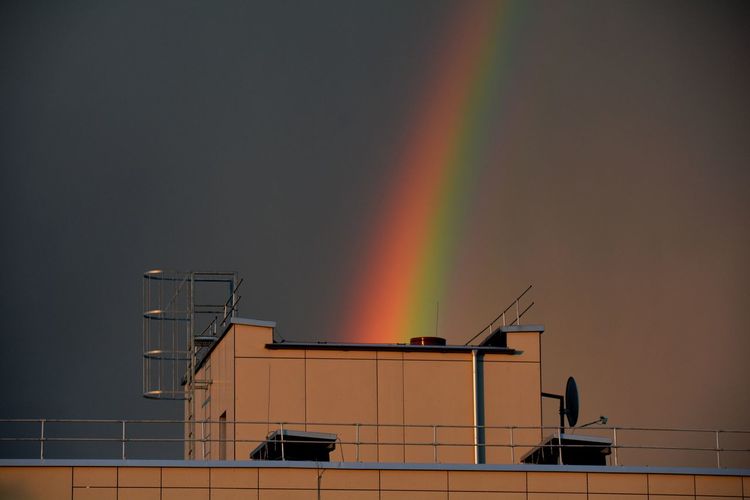 Low angle view of rainbow over building against sky