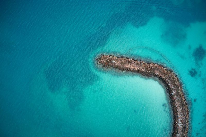 Aerial view of natural stone barrier in crystal blue water on praslin, seychelles.