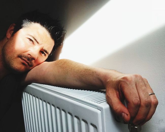 Close-up of man leaning on radiator