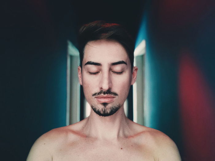 Shirtless young man with eyes closed