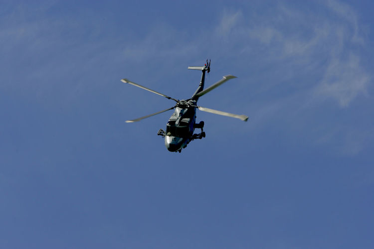Low angle view of helicopter in blue sky