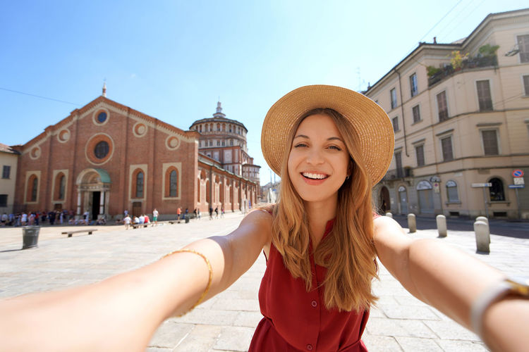 Beautiful fashion girl takes self portrait with the church of santa maria delle grazie