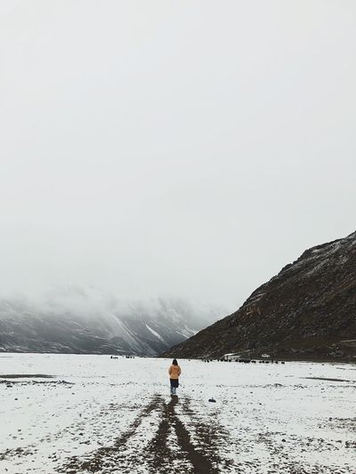 Rear view of person on snow covered mountain against sky