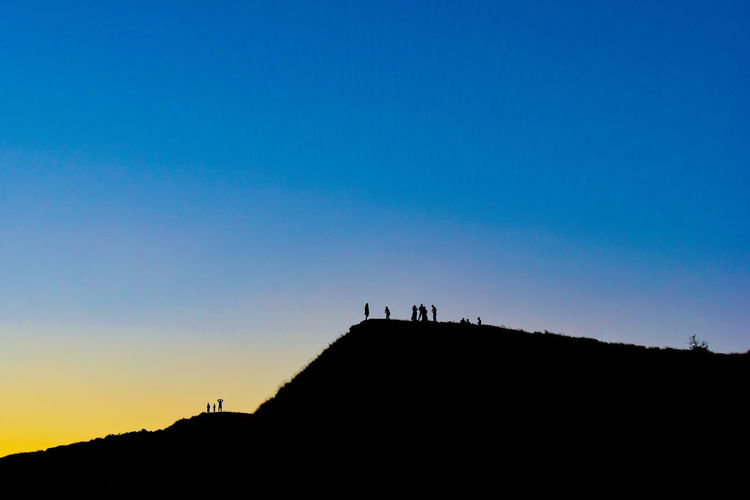 Silhouette people against clear sky during sunset