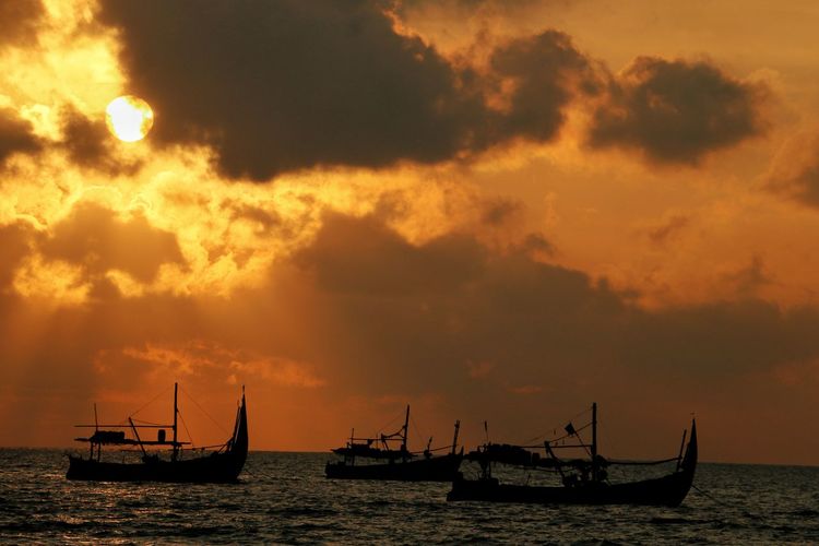 Silhouette sailboats in sea against sky during sunset