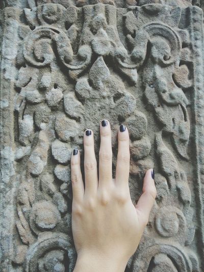 Cropped hand of woman touching carved wall