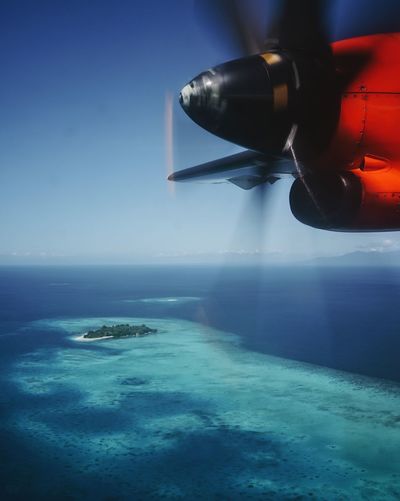 Close-up of airplane flying over sea against clear sky