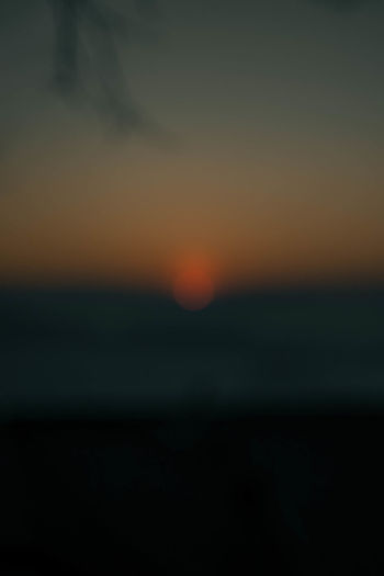 Defocused image of sea against sky at sunset