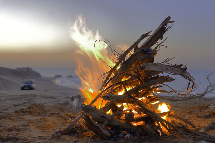 Bonfire on land against sky during sunset