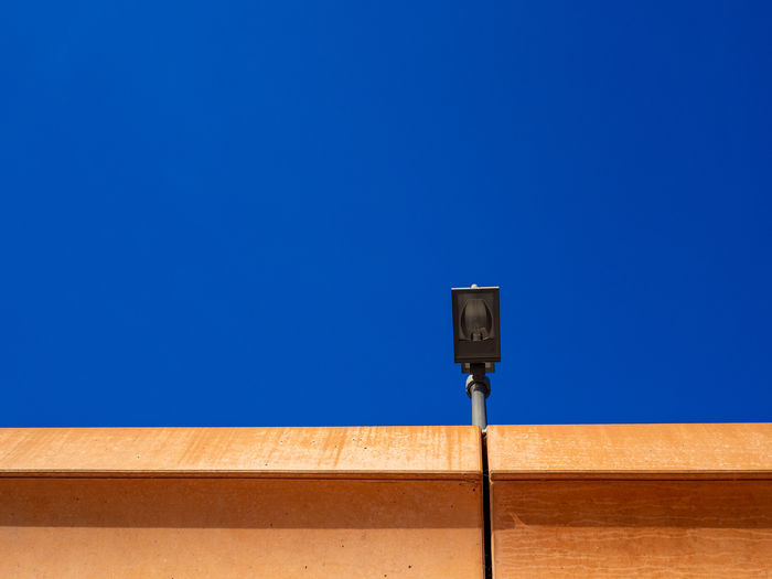 Low angle view of lighting equipment against clear blue sky