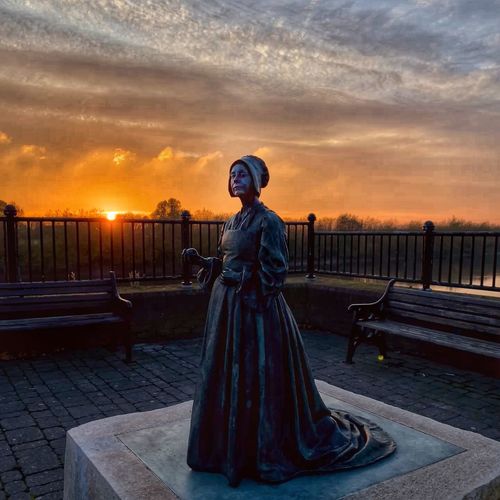 Sculpture of pilgrim woman at sunset