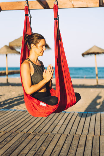 Woman meditating while sitting on silk at beach