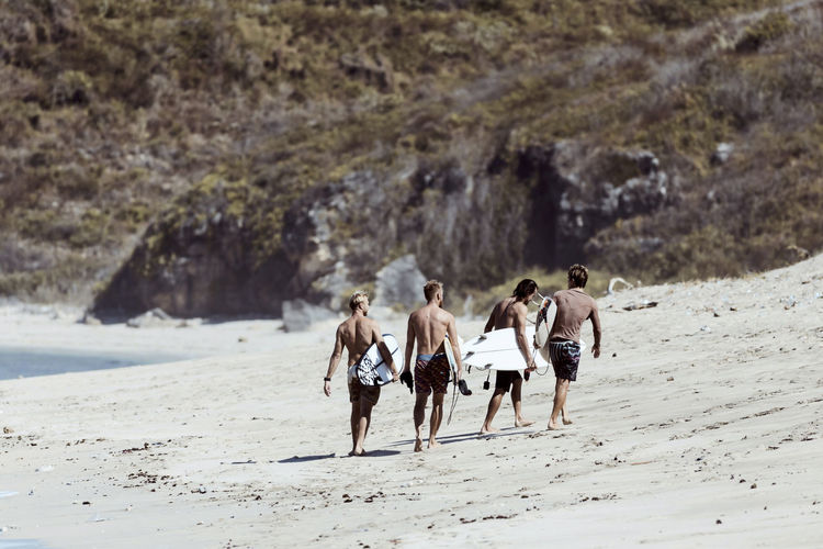 Unrecognizable surfers walking towards cliff