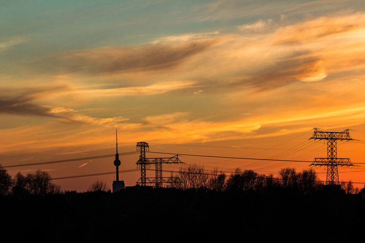 Silhouette electricity pylon against sky during sunset