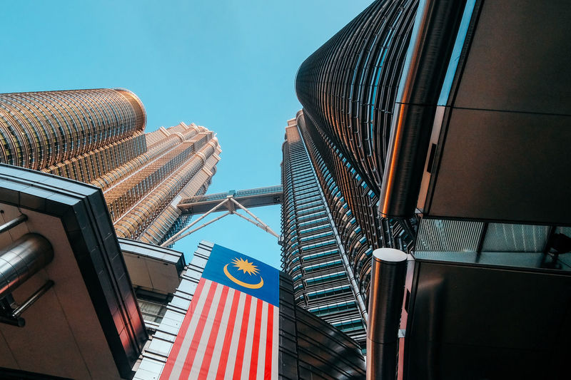 Low angle view of a flag on a twin towers building against blue sky