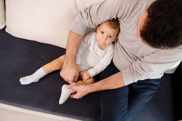 High angle view of father with son sitting on sofa at home
