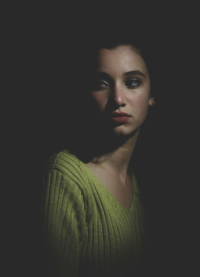 Thoughtful young woman looking away while standing against black background