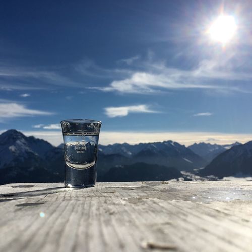 Close-up of beer on table by mountains against sky