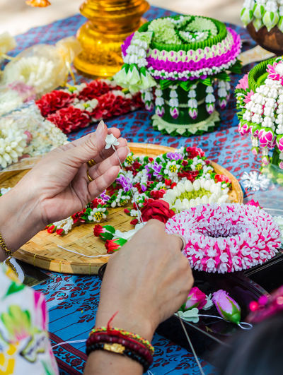 Cropped hands of woman making floral garland