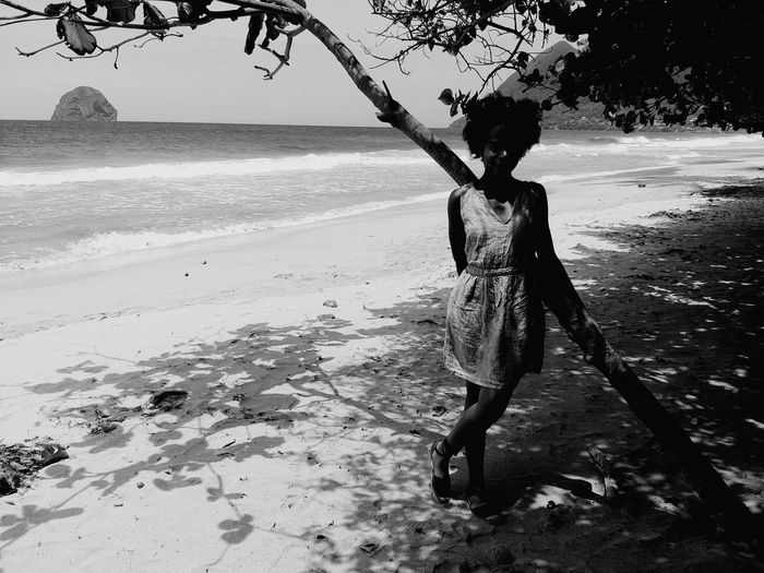 Woman standing against tree at beach