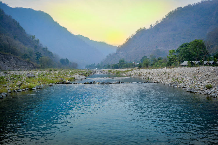 Scenic view of river by mountain during sunrise