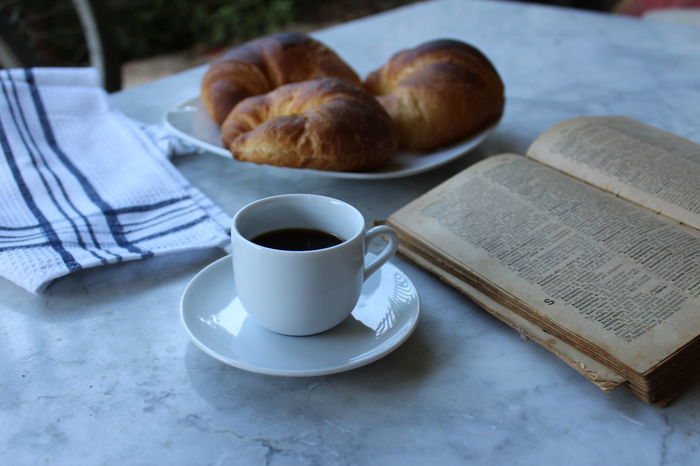 Croissants with coffee and book on table