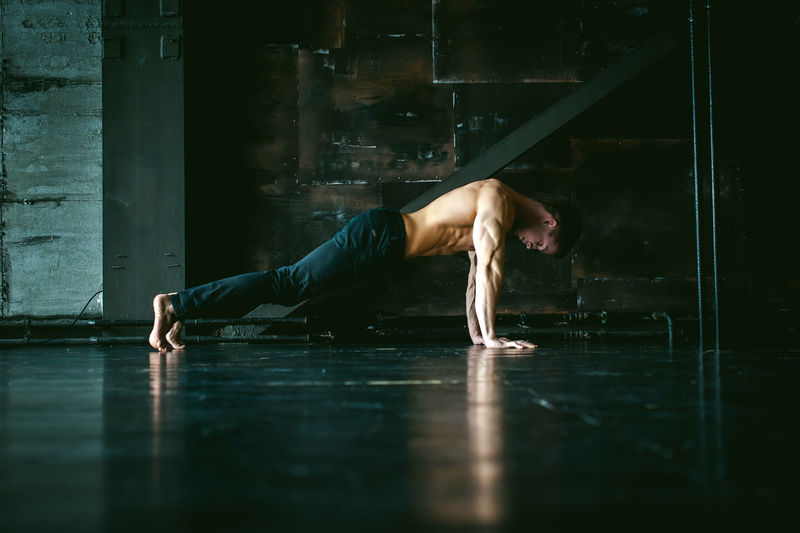 Full length of shirtless man exercising on floor