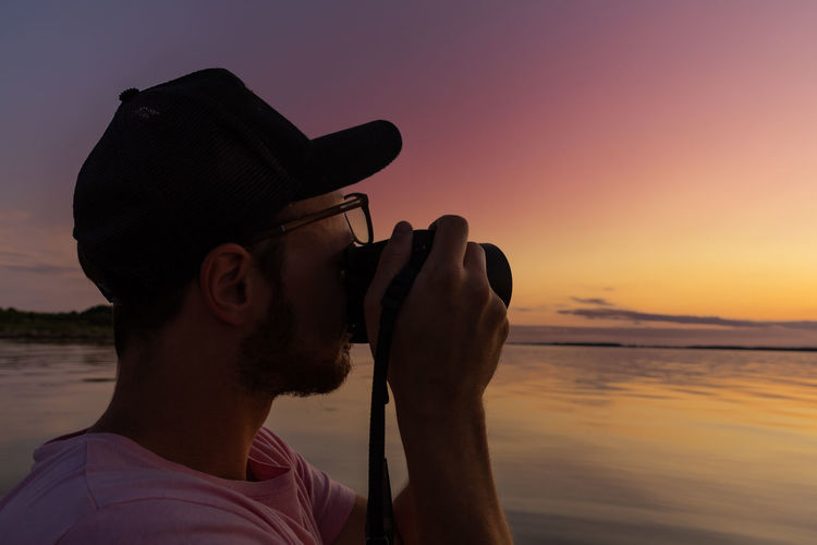 Man photographing against sky during sunset