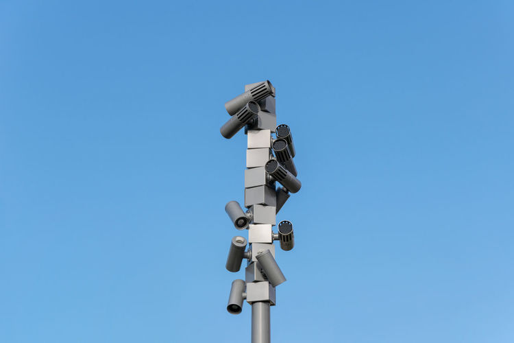 Low angle view of security cameras against clear blue sky