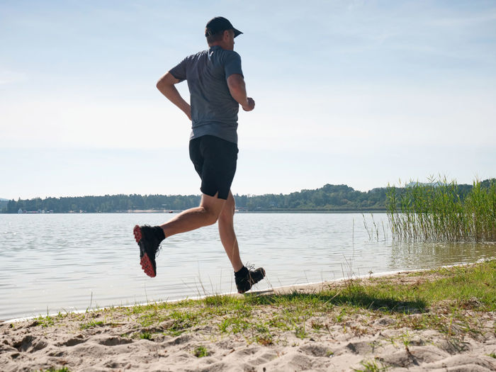 Man exercising on the beach. active man exercising and stretching on the lake beach at sunrise