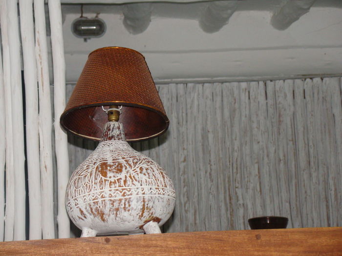 Close-up of lantern hanging on table against wall at home