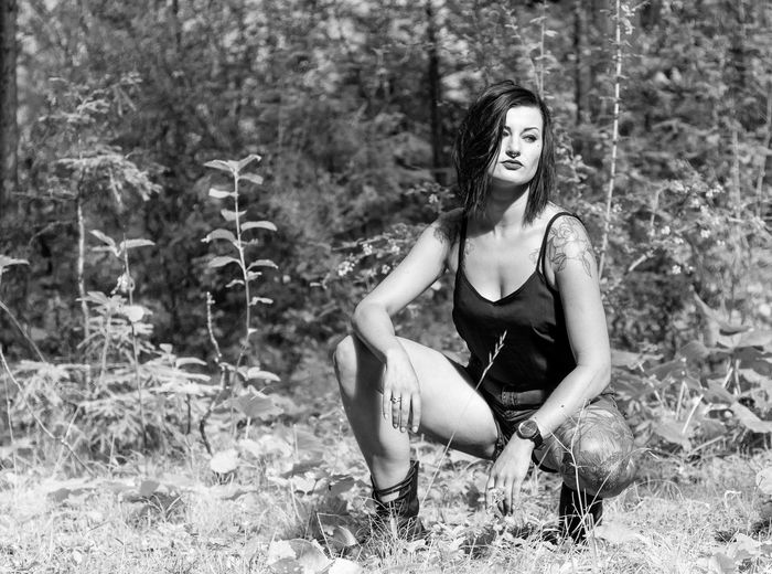 Portrait of woman sitting on field in forest