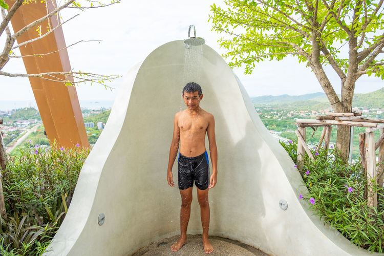 Full length of shirtless boy taking bath outdoors