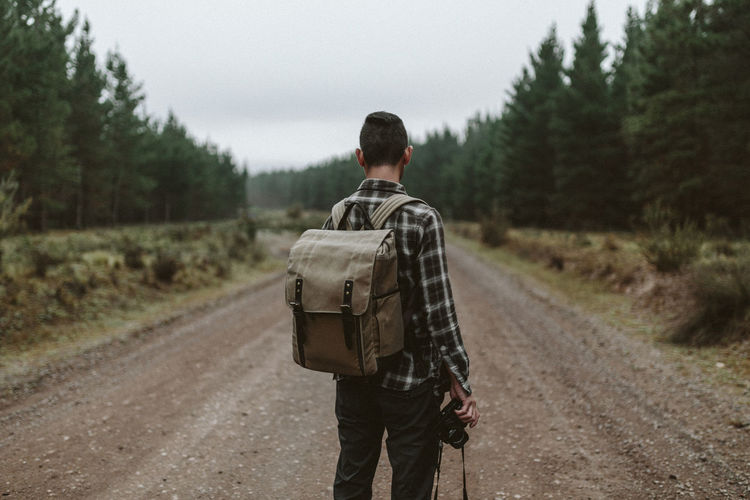 Rear view of a man walking on countryside landscape
