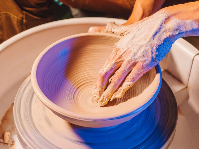 Cropped hand of potter making pot using pottery wheel in workshop