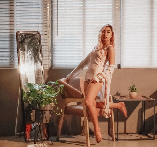 Sensual woman by chair looking away at home