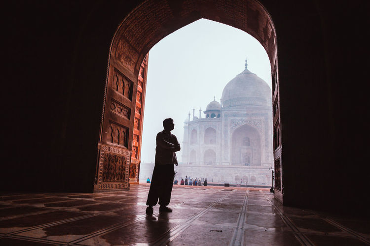 Silhouette man standing by arch against taj mahal