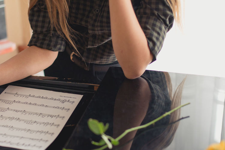 Midsection of woman sitting with musical note
