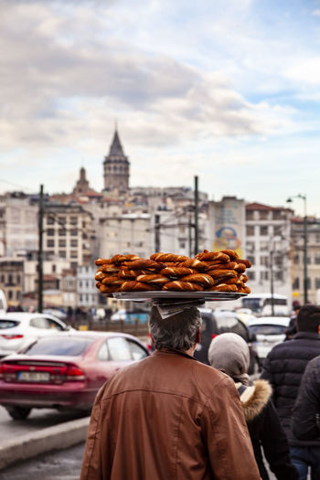 Rear view of man selling food in city against sky