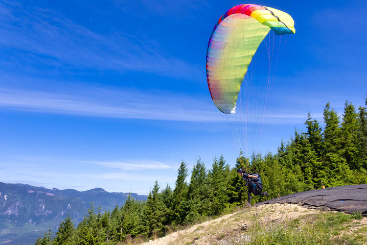 Man paragliding over mountain against sky