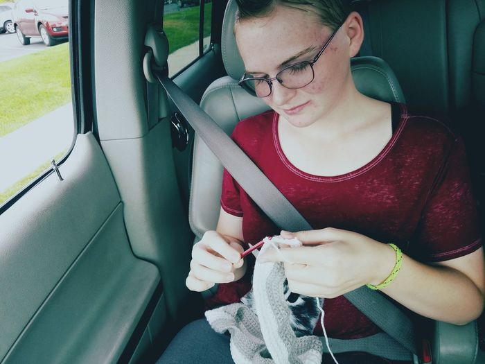Woman crocheting while sitting in car