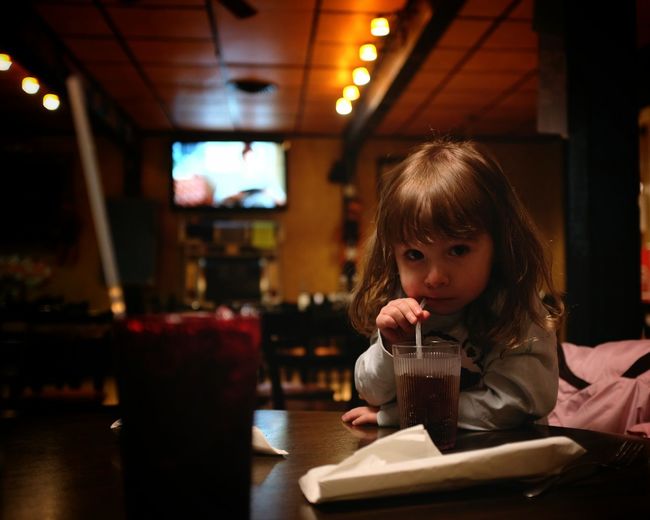 Portrait of cute girl drinking soda in restaurant