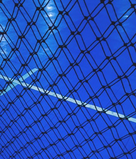 Low angle view of chainlink fence against blue sky