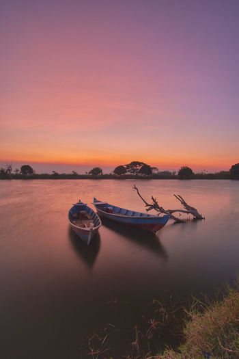 Two empty wooden boats for fishing on a calm water lake at sunset