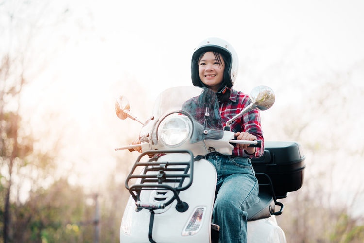 Portrait of young woman riding motor scooter on road