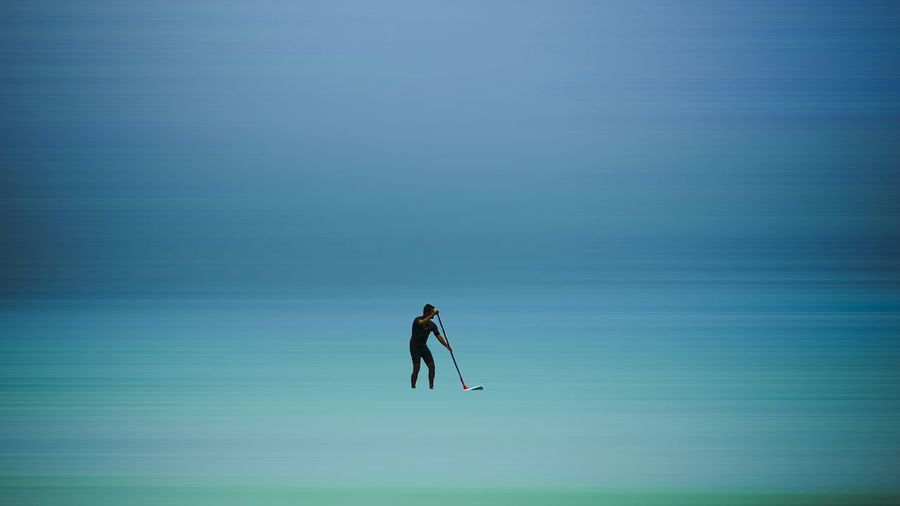 Man paddleboarding in sea against sky